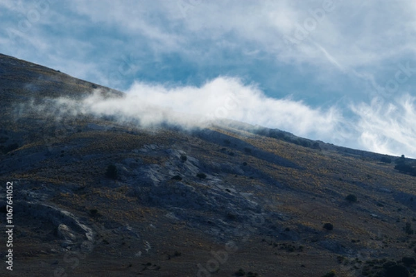 Fototapeta Majestic mountain landscape with swirling clouds and clear sky