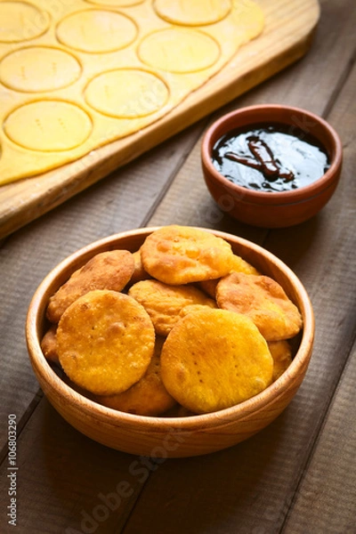 Obraz Tradycyjne chilijskie ciasto smażone Sopaipilla z puree z dyni w cieście, podawane ze słodkim sosem Chancaca, fotografowane na drewnie przy naturalnym świetle (Selective Focus)