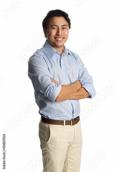 Fototapeta A calm relaxed man wearing a light blue shirt with beige pants, standing against a white background. Carefree and relaxed looking at camera.