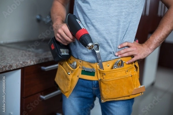 Obraz Midsection of man holding cordless hand drill 