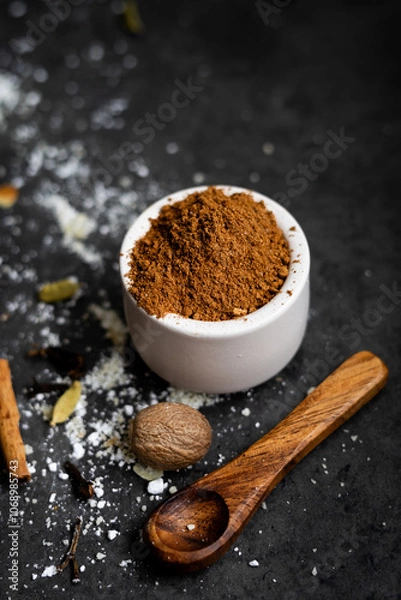 Obraz Selbstgemachte Spekulatius Gewürzmischung in kleiner Schale mit Holzlöffel, Puderzucker, Zimtstange, Kardamon Nelke und Muskatnuss