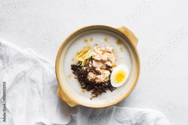 Fototapeta Overhead view of rice chicken congee with ginger and caramelized onions in a clay pot, top view of rice and chicken porridge, chinese chicken congee, korean dak juk or japanese okayu in a claypot