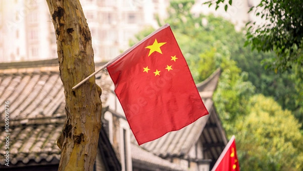 Fototapeta Chinese flag with bright red and yellow colors is mounted on tree