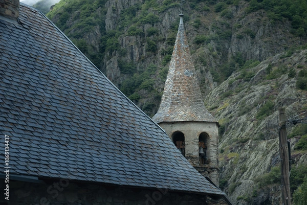 Fototapeta Detail of a black slate roof typical of the Pyrenees mountains with a church tower in the village of Unha, near Baqueira in Spain