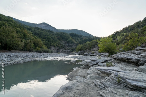 Fototapeta Osumi Gorge, Albania - August 15 2024: Stunning view of Osumi Canyon (Albanian: Kanioni i Osumit), showcasing the breathtaking cliffs, vibrant greenery, and winding river through dramatic landscape.