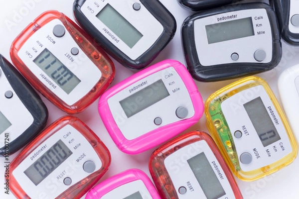 Fototapeta Pile of colorful pedometers over white background