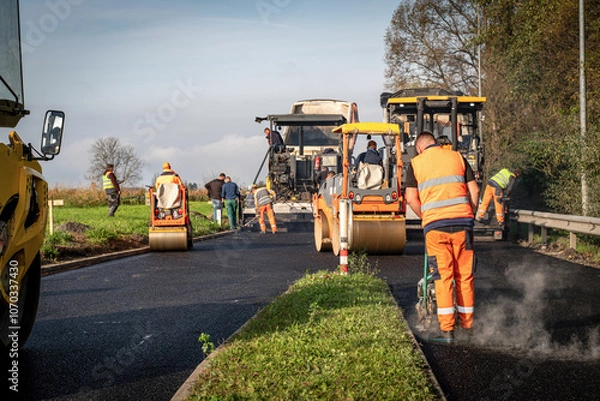 Fototapeta Complete Asphalt Laying Process with Paver, Compact Roller, Handheld Compactors, and Construction Workers