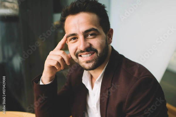Fototapeta Portrait of handsome smiling businessman in formal wear using mobile phone for chatting online having break in cafe interior, positive successful male entrepreneur looking at camera enjoy devices