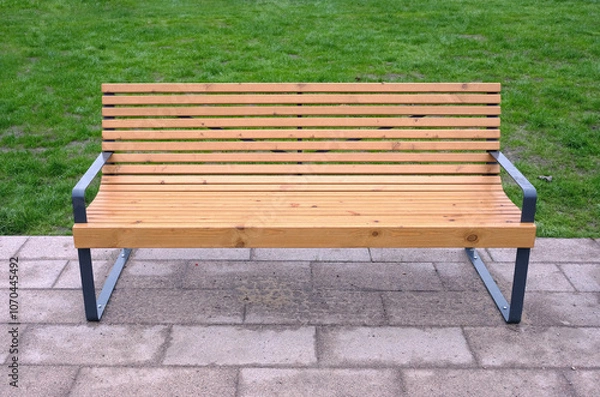Fototapeta Empty modern sandy brown wooden bench in the park way against green grass front view