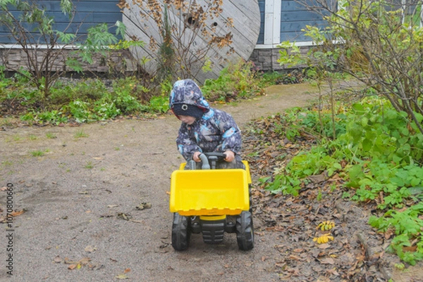 Fototapeta a child boy on a wheeled bulldozer tractor, photo without filters