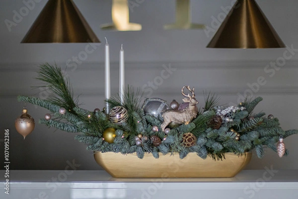 Obraz Christmas table composition made of fresh nobilis spruce, white candles, pine branches with glass balls and decorative gold deer. Happy New Year decorations.