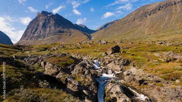 Obraz Under the Kebnekaise summit with mountains, dramatic peaks, valley, stream and swedish wilderness of nordic landscape during autumn beautiful day in Sweden while hiking and backpacking epic nature.
