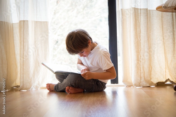 Fototapeta niño leyendo un libro en casa