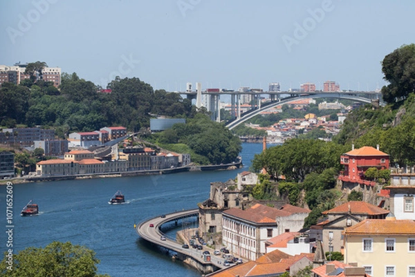 Fototapeta A view over the river Douro at the harbour of Porto in Portugal. The 70 m high bridge of Ponte da Arrábida, which is close to the mouth of the River and the Atlantic Ocean, is visible in the distance.