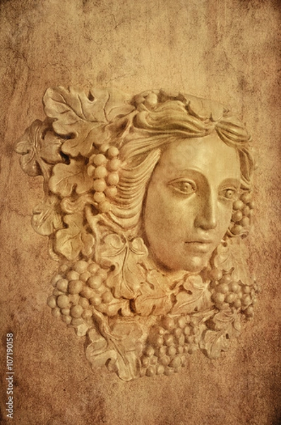 Fototapeta Textured Background of Grape haired Greek woman sconce statue/Textured Background with bust head of a Greek maiden with grapes leaves in statue form