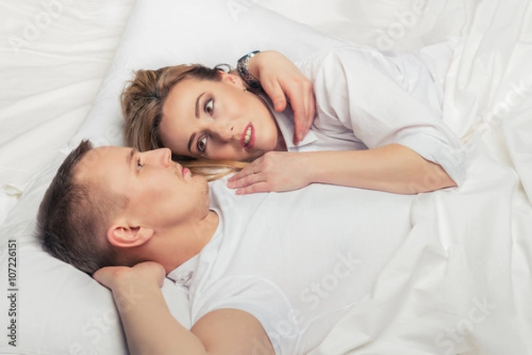 Fototapeta Young couple lying in bed.
