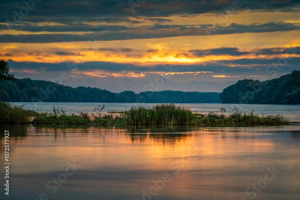 Fototapeta Sunrise idyll landscape on a river with a cloudy sky at golden hour