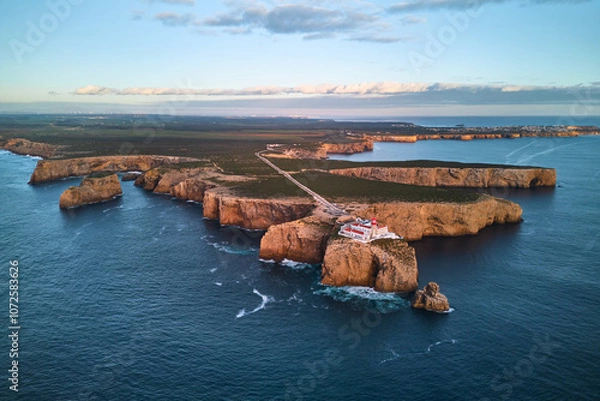 Fototapeta The lighthouse of Cabo de São Vicente and fort ruins at sunset. Aerial view from the ocean
