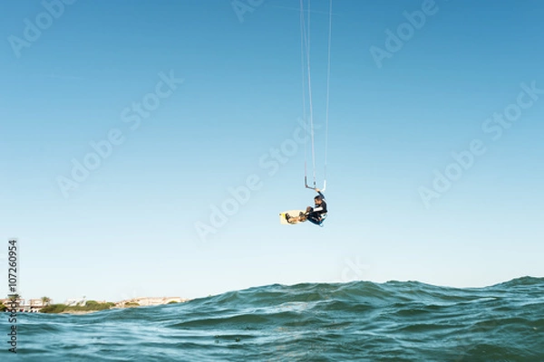 Fototapeta Surfer jumping in front of the beach