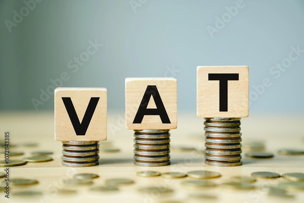 Fototapeta VAT Concept with Wooden Blocks Placed on Stacks of Coins Representing Value Added Tax in Finance, Taxation, and Business Economics