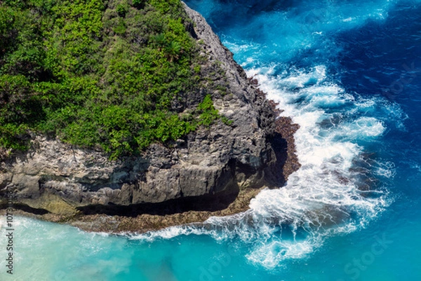 Obraz Majestic cliffs stand tall as powerful waves crash against them, sending sprays of mist into the air. A stunning dance of nature's strength and beauty in Nusa Penida of Bali.