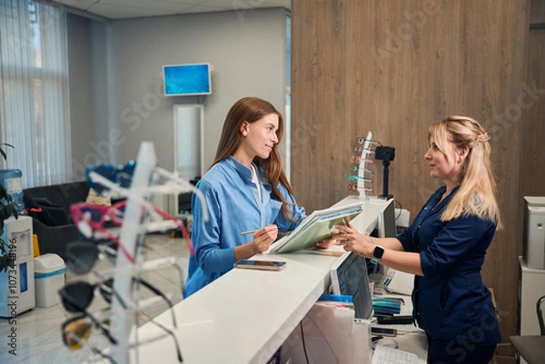 Fototapeta Patient and receptionist discussing paperwork at the counter