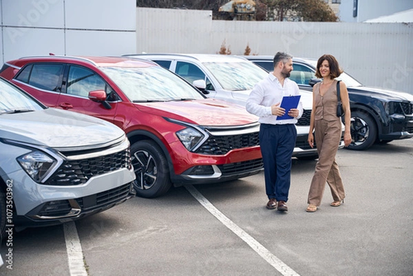 Obraz Female client talking with salesman manager at car salon showroom outdoors