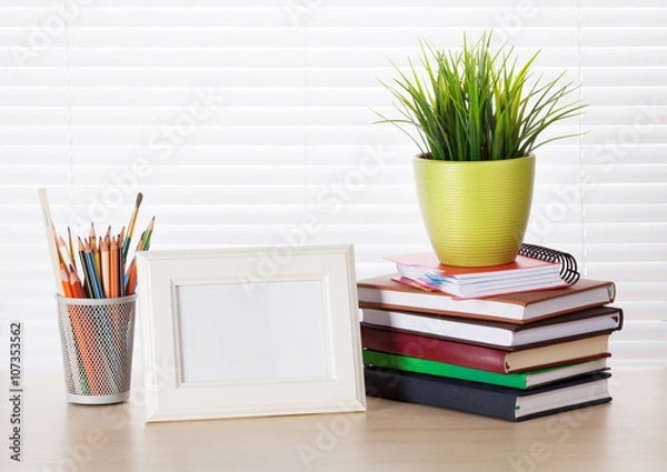 Fototapeta Workplace with photo frame, pencils, books