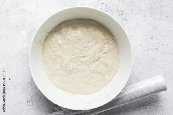 Fototapeta Overhead view of nigerian puff-puff dough that has proofed, puff-puff dough in a white mixing bowl, process of making puff-puff or bofrot