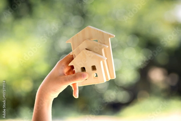 Obraz Man hand hold for select the three home model on sunlight building background, Loan for real estate or saving money for buy a new house to family in the future concept.
