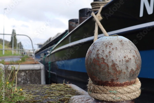 Obraz The boat is sucured to the dock with a rope tied to a steel mooring boarding pole