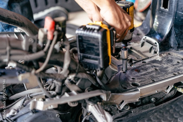 Obraz Mechanic use electric screwdriver or impact driver to repair motorcycle in garage, Maintenance and repair motorcycle concept