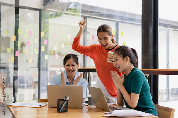 Fototapeta Excited Asian businesswoman team working together in office, About successful startup projects concept.