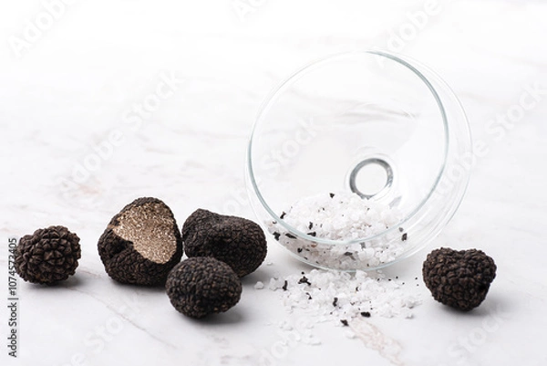 Fototapeta Truffle salt and truffle on the white table, how to preserve the aroma and taste of black truffle. Preserving black truffle. Delicacy condiment for flavoring dishes, front view