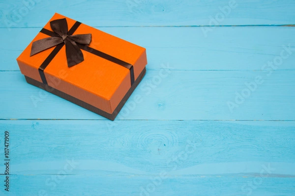 Obraz orange gift box on a blue wooden background