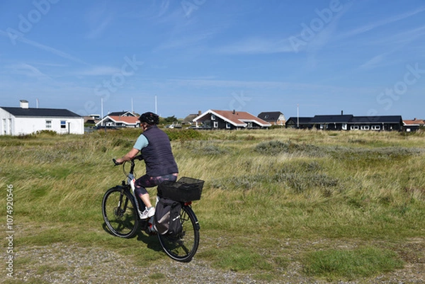 Fototapeta Frau fährt mit dem Fahrrad durch Dänemark