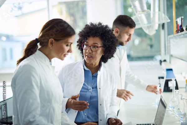 Fototapeta Female scientists talking while working together in laboratory. 