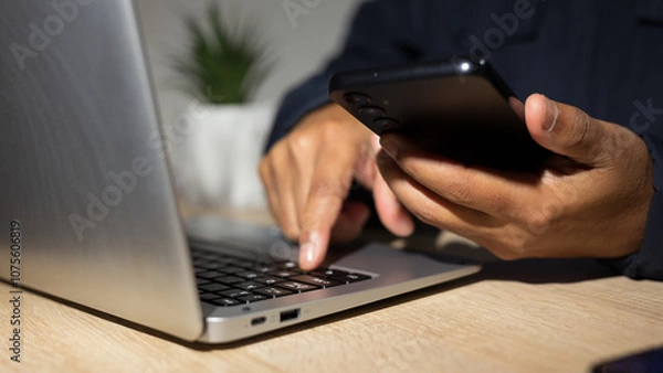 Obraz Businessman using smartphone and typing on laptop keyboard for cybersecurity and privacy