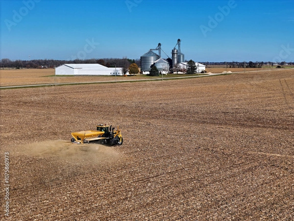 Fototapeta Self-propelled application vehicle spreading agricultural lime on a farm field to increase the soil's pH level. With farm scene in the background.