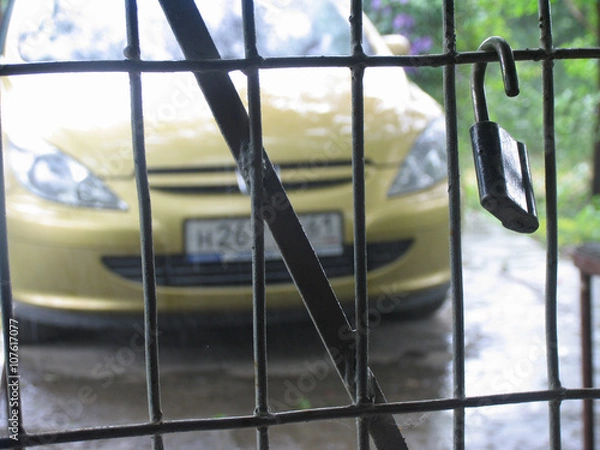 Fototapeta Lattice with hang padlock and yellow car on background