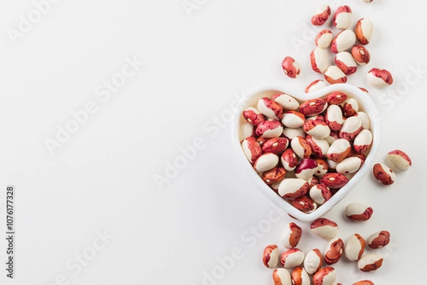 Fototapeta Heart shape  bowl with red and white kidney beans and scattered  on white background  top view whith copy space
