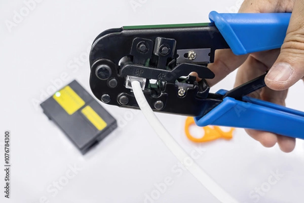 Obraz An IT network engineer using a crimping tool to attach an RJ45 connector to a network cable.