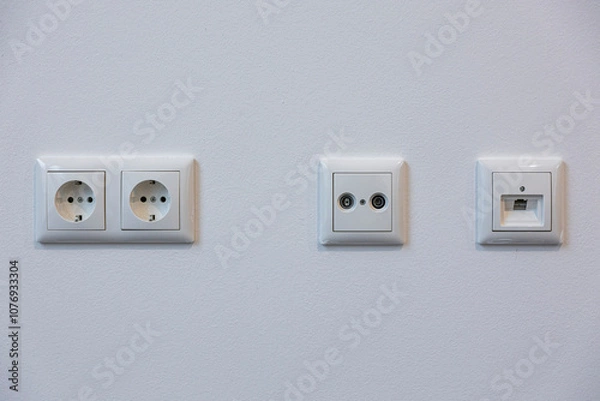 Fototapeta Power outlets, a TV cable connection, and a plan connection on a modern wall panel, offering essential connectivity for home entertainment and functionality.