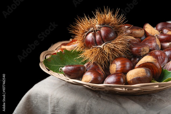 Fototapeta Chestnuts with leaves and burs on a wooden table