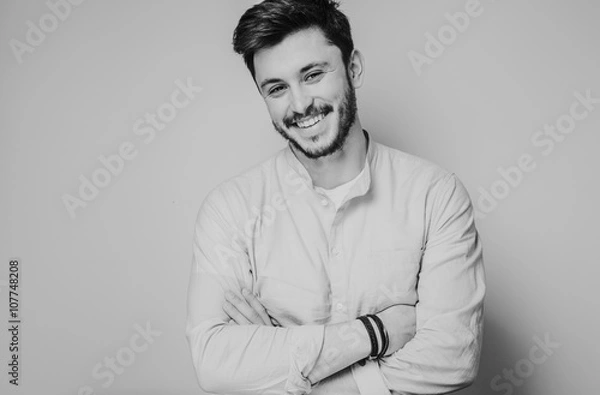 Obraz black and white portrait of handsome smiling man isolated on gray studio background posing to the camera