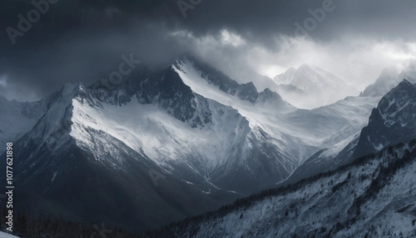 Fototapeta Snowstorm Sweeping Across Rugged Snowy Mountain Range with Dark Clouds and Heavy Snowfall