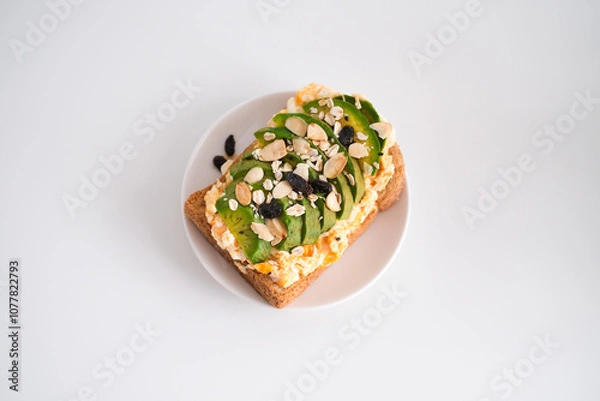 Fototapeta Avocado sandwich with scrambled eggs, sliced avocado and egg on toasted bread for healthy breakfast or snack.