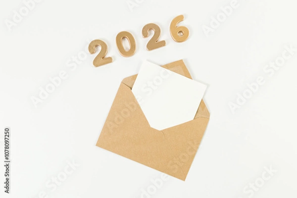 Fototapeta 2026 Happy New Year. Top view of gold numbers, brown kraft envelope, white card on white background. Copy space, flat lay.