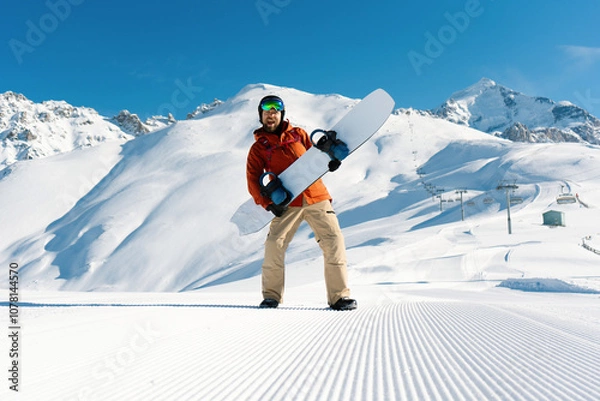 Fototapeta Happy snowboarder have fun holding snowboard standing and posing along ski slope at  resort prepared by snowcat