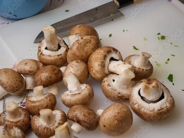 Obraz Washed champignon mushrooms on a cutting board with a knife. Cooking pasta with mushrooms and bacon. Classic Italian cuisine.